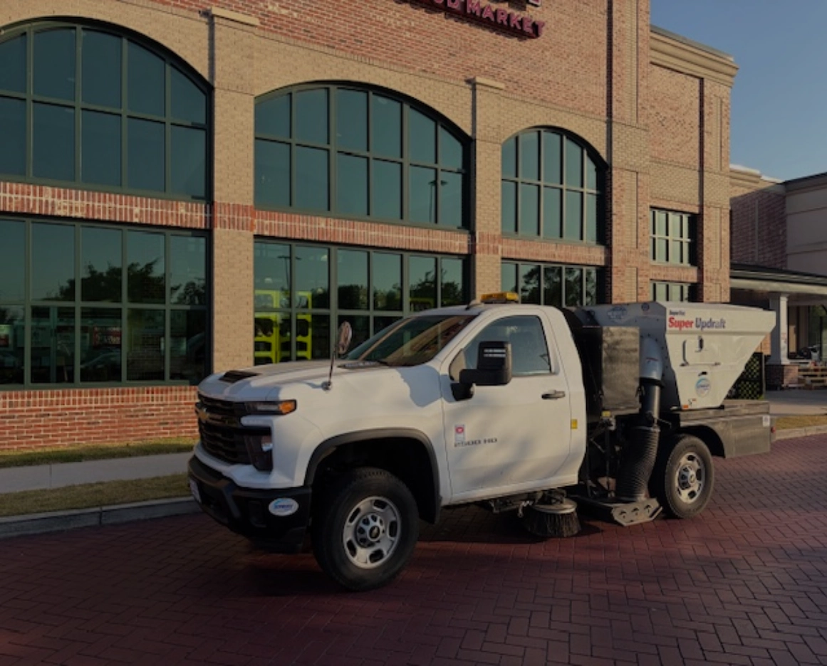 White utility truck parked outside a commercial building at sunset.
